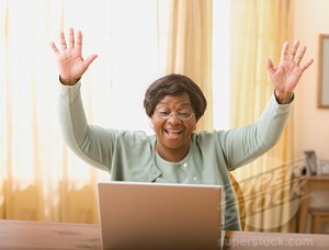 Senior African woman cheering next to laptop