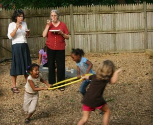Children play with hula hoop while parents eat