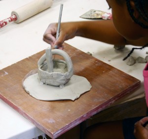 Girl works on clay basket